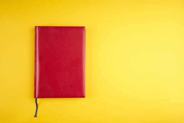 blank red leather diary on yellow trendy background. copy space. top view - Zdjęcie, obraz
