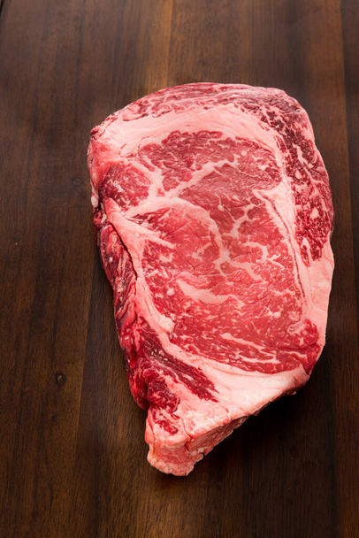 A raw New York strip Ribeye steak thick steak on a cutting board. - Photo, Image