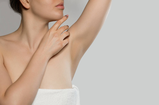 Armpit epilation, lacer hair removal. Young woman holding her arms up and showing clean underarms, epilation on smooth clear skin .Beauty portrait. Skin care.  - Fotó, kép