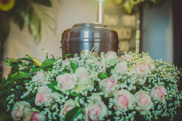 A metal urn with ashes of a dead person on a funeral with noone around on a memorial service. Sad grieving moment at the end of a life. Last farewell to a person in an urn. - Photo, Image