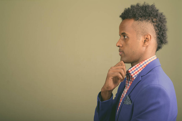 Jonge knappe Afrikaanse zakenman draagt pak tegen gekleurde achtergrond - Foto, afbeelding