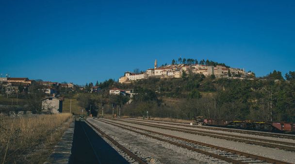 A híres város Stanjel, egy falu egy dombon a Karszt régió Szlovénia egy napsütéses napon, kilátás nyílik a vasútállomáson platform. - Fotó, kép