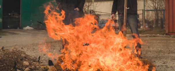 Dois homens queimando um fogo de papel em um espaço aberto. Queimar resíduos de papel em ambiente residencial ou industrial. Poluição com papel queimado. - Foto, Imagem
