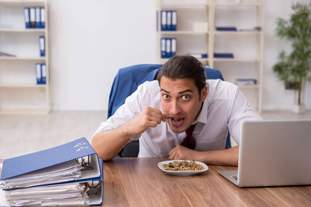 Affamato dipendente maschio mangiare grano saraceno durante la pausa - Foto, immagini