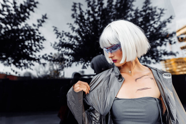 Stylish blonde in futuristic clothes and glasses on a mirror background. - Fotoğraf, Görsel