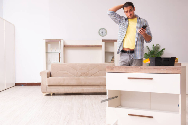 Jovem carpinteiro masculino reparando móveis em casa - Foto, Imagem