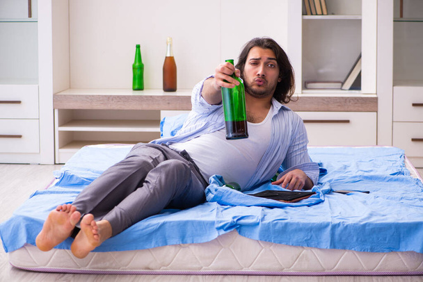 Молодий чоловічий алкоголік у спальні
 - Фото, зображення
