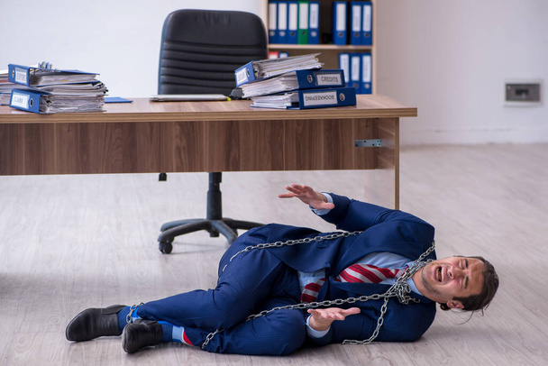 Enchaîné employé masculin mécontent du travail excessif dans le bureau - Photo, image