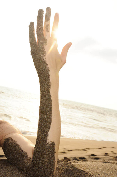 χέρι και χέρι μισοσκεπασμένο με άμμο στην παραλία - Φωτογραφία, εικόνα