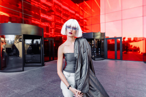 Estilo futurista. Mujer con gafas y cerca de un edificio futurista rojo. - Foto, imagen