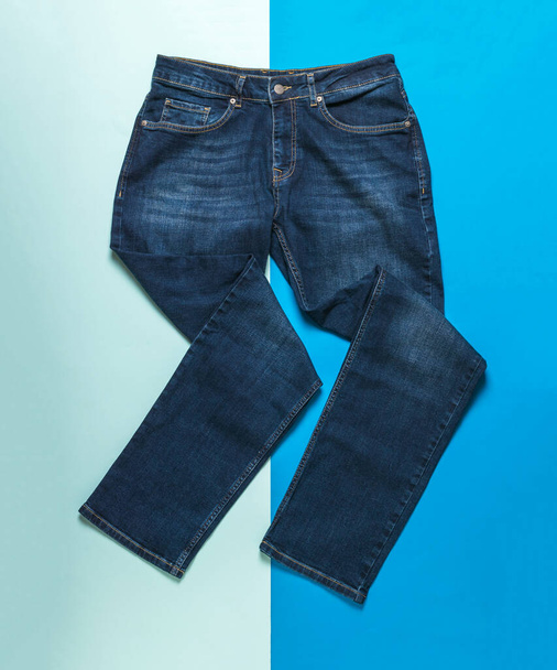 Jeans homme fantaisiste plié sur un fond bleu clair et foncé. Jeans et vêtements en denim. - Photo, image