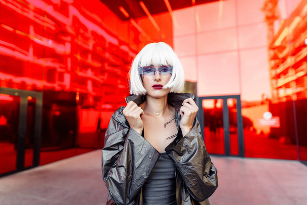Futuristic style. Woman with glasses and near a red futuristic building. - Foto, imagen
