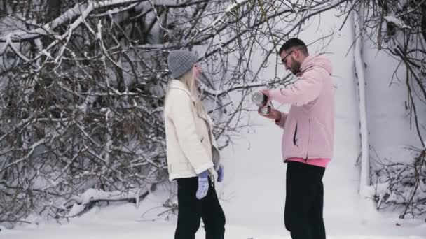 Junger Mann schenkt seiner Freundin Tee aus Thermoskanne ein - Filmmaterial, Video