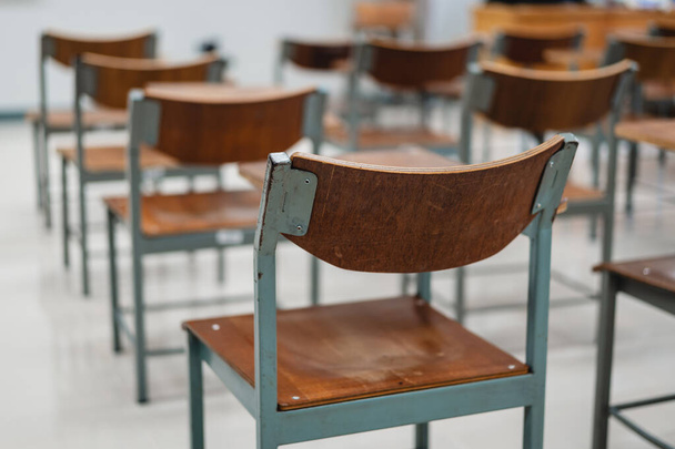 Empty university classroom with many wooden chairs. Wooden chairs well arranged in college classroom. Empty classroom with vintage tone wooden chairs. Back to school concept. - Foto, afbeelding