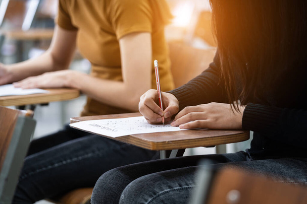 Jovens universitárias concentram-se em fazer exames em sala de aula. Alunos escrevem seriamente o exercício dos exames em sala de aula. - Foto, Imagem