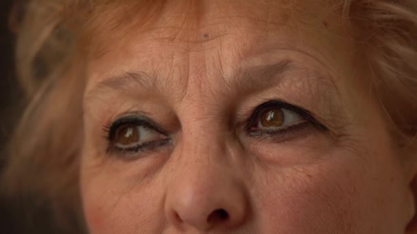 Makró felvétel a végzős nő arcáról. Vágott portré idős nő arcáról ráncokkal a barna szeme körül. Közelkép a szemek súlyos érett nő - Felvétel, videó