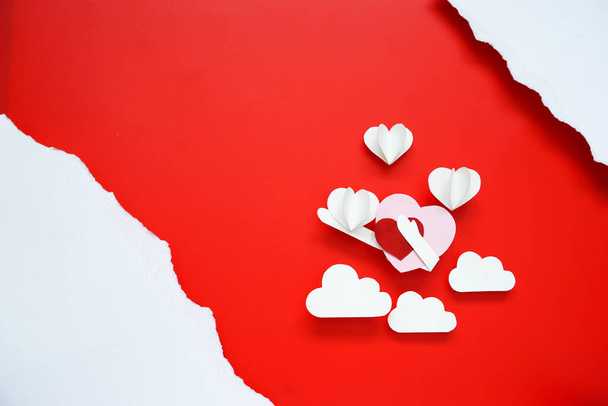 Concept de fond Saint-Valentin avec du papier blanc découpé en forme de cœur placé sur fond rouge - Photo, image