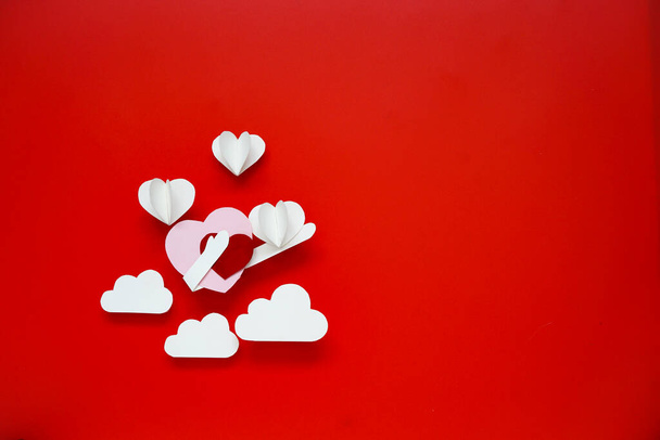Papier découpé en forme de cœur placé sur fond rouge, concept de fond de Saint-Valentin. - Photo, image