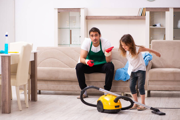 Young male contractor cleaning the house with his small daughter - Фото, зображення