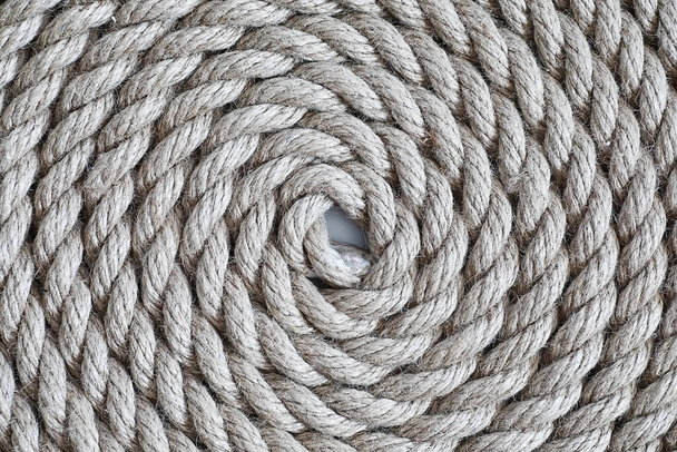 Geflochtenes dickes Seil, zu einem Knäuel gebunden. Hanfseil für Dekoration und Design. Hintergrund aus der Fischerei. - Foto, Bild