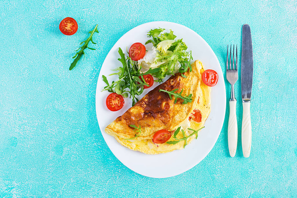 La colazione. Omelette con pomodori, formaggio e rucola su piatto bianco. Frittata - frittata italiana. Chetogeno, keto food. Vista dall'alto, piatta - Foto, immagini