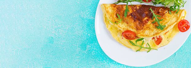 Reggeli. Omlett paradicsommal, sajttal és arugulával fehér tálcán. Frittata - olasz omlett. Ketogén, ketokonzerv. Felülnézet, zászló - Fotó, kép