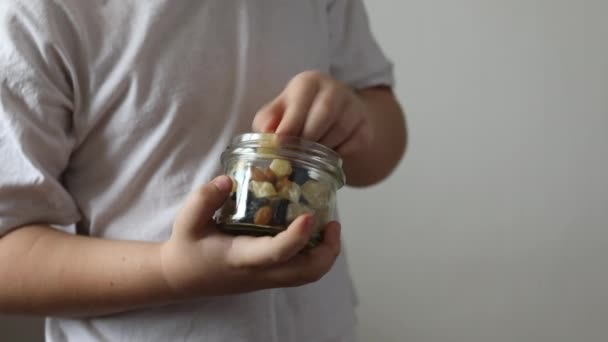 Der Junge beißt Trockenfrüchte aus Glas. Das Konzept der richtigen Ernährung, gesunde Snacks. - Filmmaterial, Video
