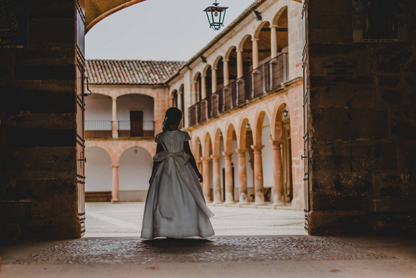 A shallow focus shot of a young girl in a white elegant dress walking to the beautiful palace - Foto, afbeelding