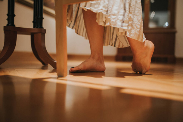 A closeup shot of female feet who is wearing a long dress and standing on the floor - Foto, afbeelding