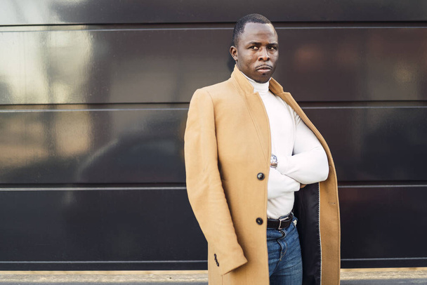 A shallow focus shot of a stylish handsome African male in a coat posing for the camera - Photo, image