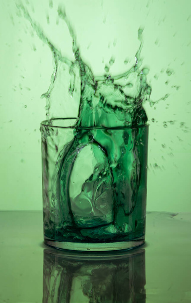 A vertical shot of a green cocktail splash on a green background - Фото, изображение