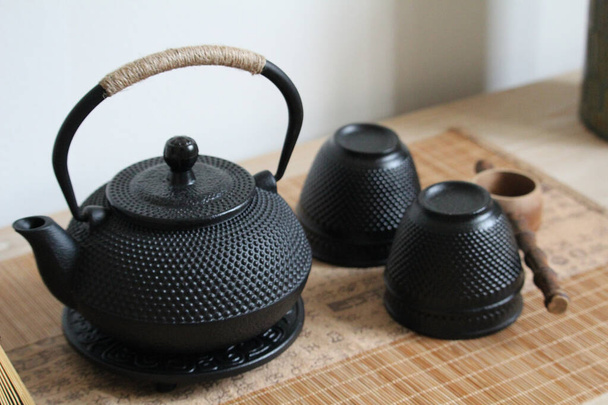 Um tiro de close-up de um bule japonês de ferro fundido, xícaras de chá e concha de madeira - Foto, Imagem