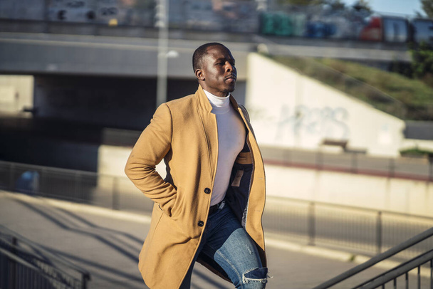 A closeup shot of a stylish handsome African male in a coat going up the stairs - Foto, Bild