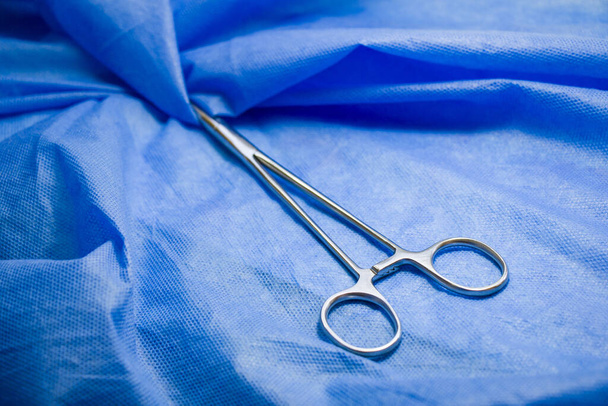 A high angle shot of a surgery forceps on the blue background - 写真・画像