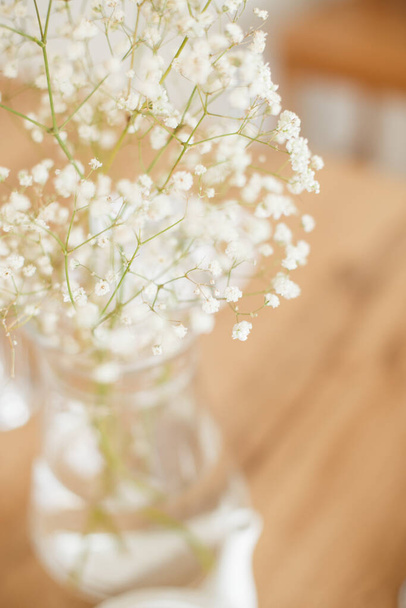 A vertical shot of a vase with small beautiful spring white flowers on the table - Photo, image