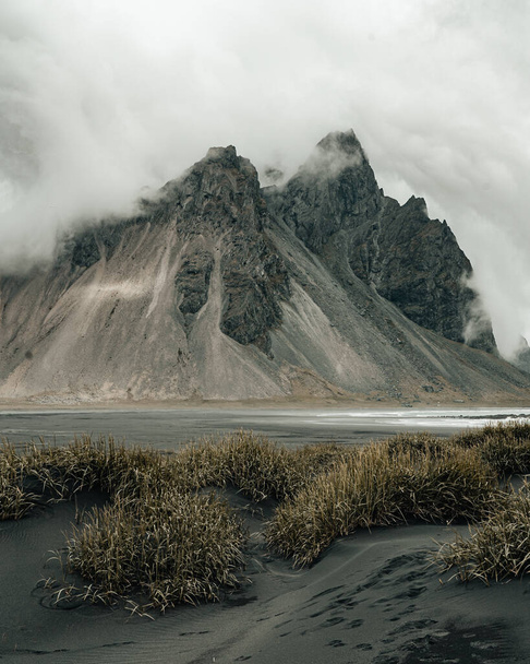 A vertical shot of the shore with black sand and sandy mountains in a foggy weather in Iceland - Φωτογραφία, εικόνα