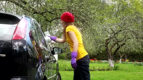 γυναίκα βερνίκι μαύρο αυτοκίνητο με σφουγγάρι αφρό έξω από τον κήπο. 4K - Πλάνα, βίντεο