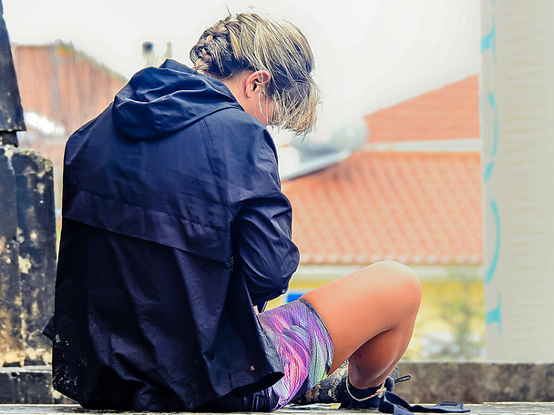Femme blonde assise sur un mur se reposant après une compétition de course - Photo, image