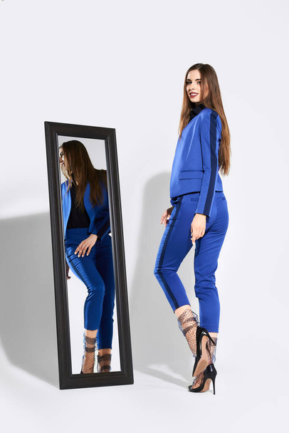 Stylish girl posing in pantsuit and tulle socks near the mirror - Zdjęcie, obraz
