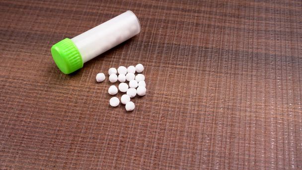 Close-up beeld van homeopathische geneeskunde bestaande uit de pillen en een fles met een vloeibare homeopathische stof. - Foto, afbeelding