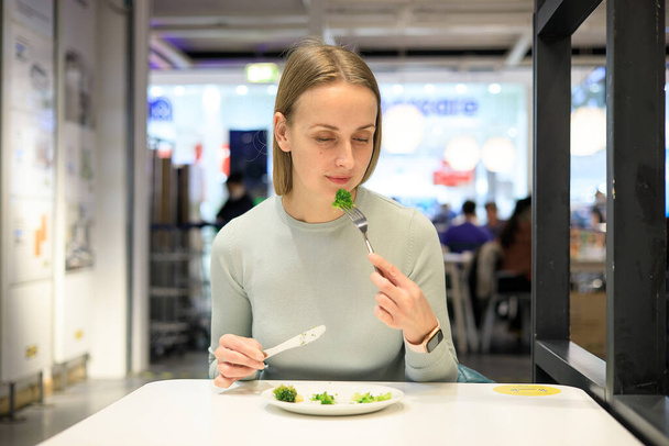 Kobieta jedząca brokuły w kawiarni - Zdjęcie, obraz