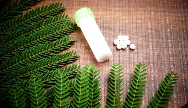 Крупним планом образ гомеопатичної медицини, що складається з таблеток і пляшки, що містить рідку гомеопатичну речовину
. - Фото, зображення