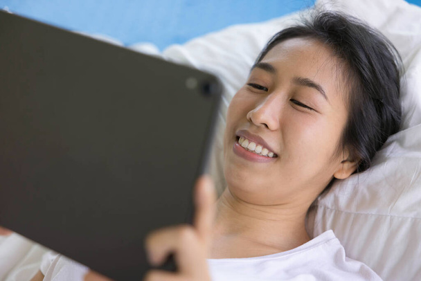 woman using digital tablet in a bed at home. The use of concept of new generation, family, parenthood, authenticity, connection, technology - Foto, afbeelding