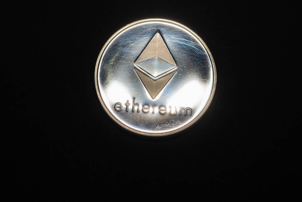 блискуча срібна ефірна монета з криптовалюти зверху посередині на чорному тлі
 - Фото, зображення