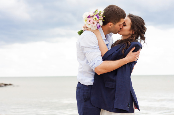 Romantic bride and groom are kissing near the sea. - Foto, Bild