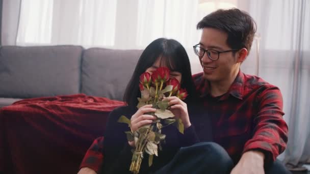 Valentinstag oder Jubiläum Konzept. Junge Frau riecht rote Rosen, während ihr Freund sie küsst und umarmt - Filmmaterial, Video