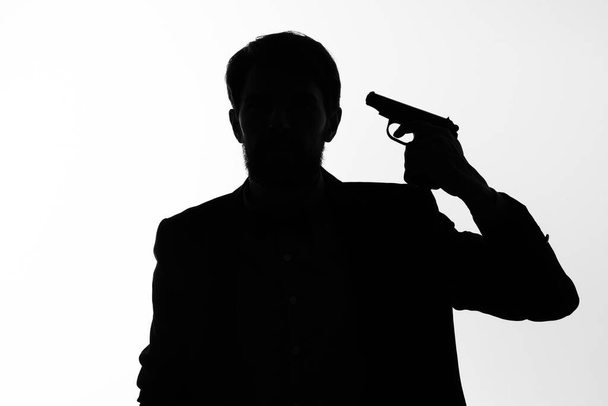 stín muže se zbraní v rukou, který míří na nebezpečí sebevraždy - Fotografie, Obrázek