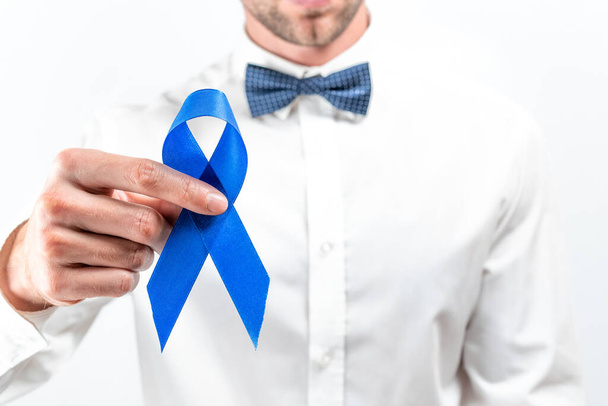 Люди с раком. Хипстеры в яркой рубашке, голубая бабочка с голубой лентой в руках на белом фоне. Осведомленность рака предстательной железы мужского здоровья. Здравоохранение и концепция Всемирного дня борьбы с раком - Фото, изображение