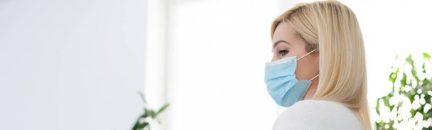 Primo piano della donna che indossa maschera protettiva, guardando da parte lo spazio copia, isolato su sfondo blu. Influenza, allergia, protezione contro il virus, pandemia di coronavirus - covid-19. - Foto, immagini