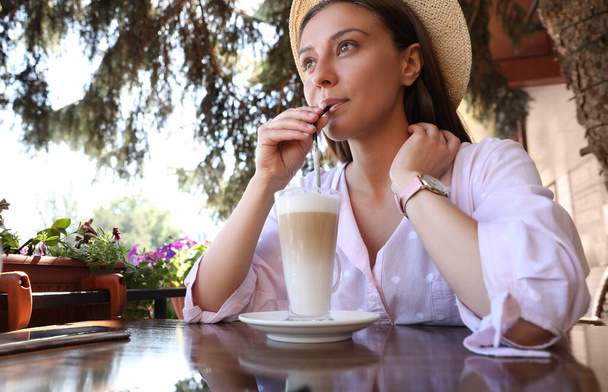 Beautiful young woman with coffee at table in outdoor cafe - Foto, Bild